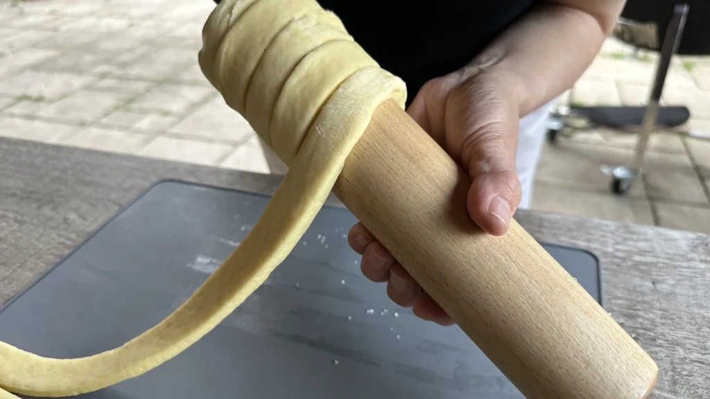 Rulează banda de aluat în spirală pe cilindrul din lemn&hellip;